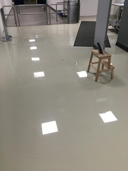 Glänzender, heller Industrieboden mit Hocker und Werkzeug im Raum.